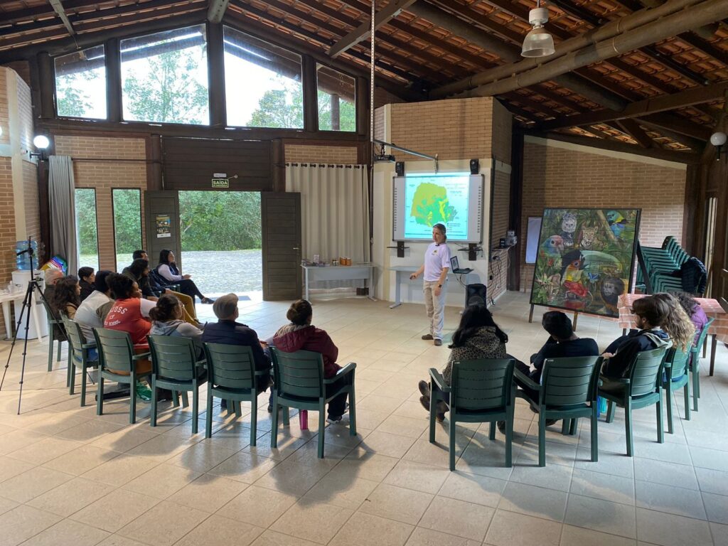 Imagem de Solange fazendo apresentação para a plateia, no Centro de Visitante da Reserva Natural.