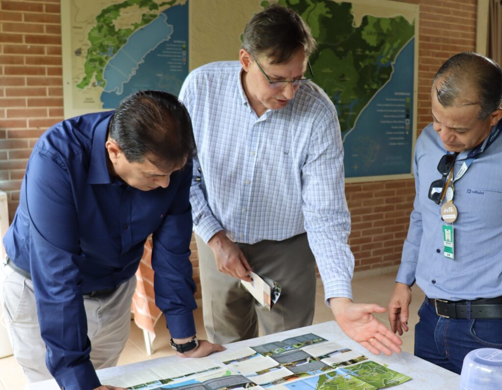 Imagem de Clóvis mostrando um mapa para dois homens.