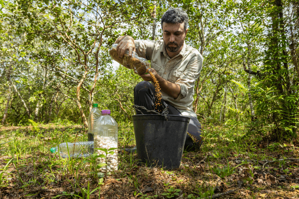 Imagem de um homem despejando sementes em um balde preto.