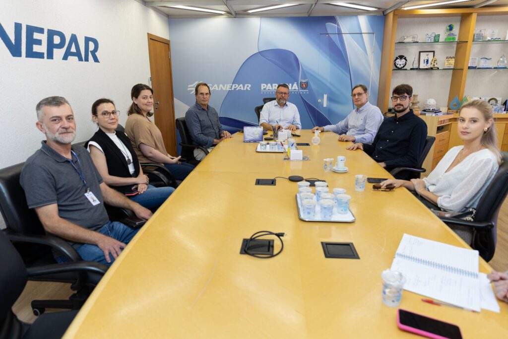 Imagem mostra oito integrantes da Sanepar e SPVS sentados a uma mesa olhando para a foto