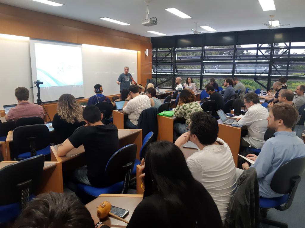 Imagem de um homem a frente da plateia.