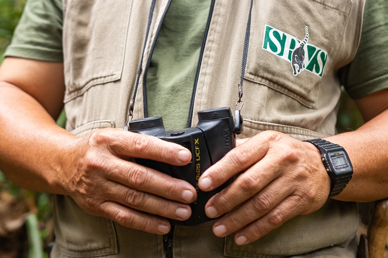 Imagem de mãos masculinas segurando um binóculo.
