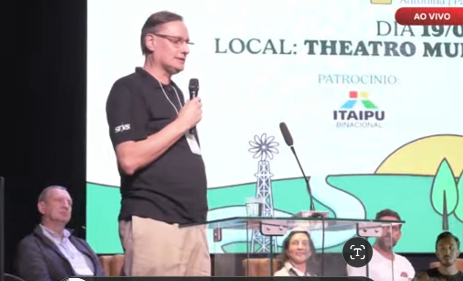 Imagem de Clóvis Borges apresentando em frente a um telão projetado.