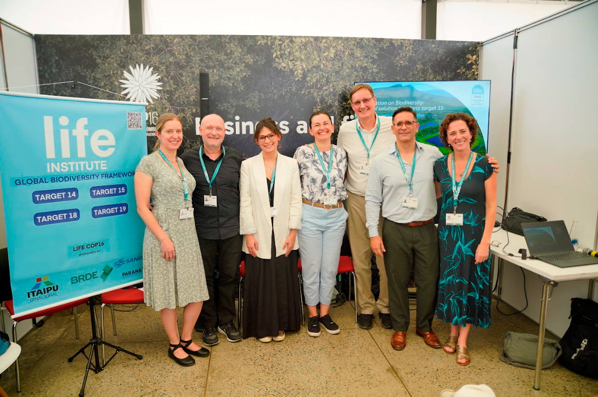 Imagem com sete pessoas brancas posando para a foto sorrindo.